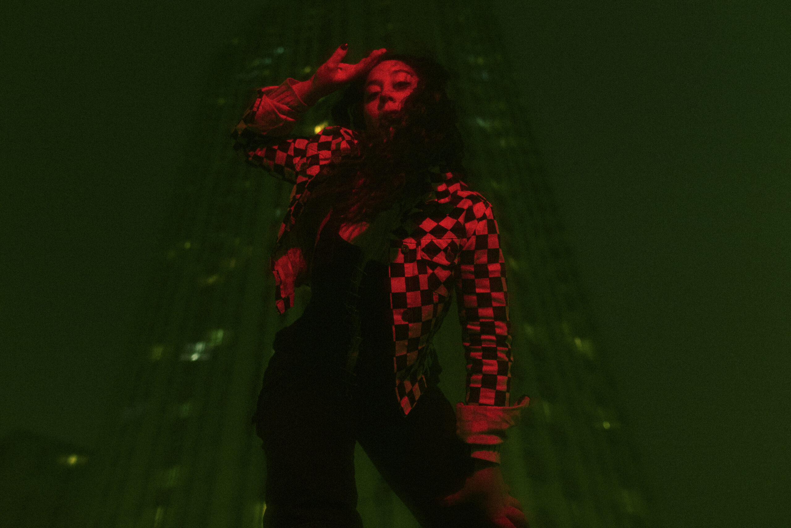 Anna Lê Quang en performance, bras levé, dans une lumière rouge et verte.