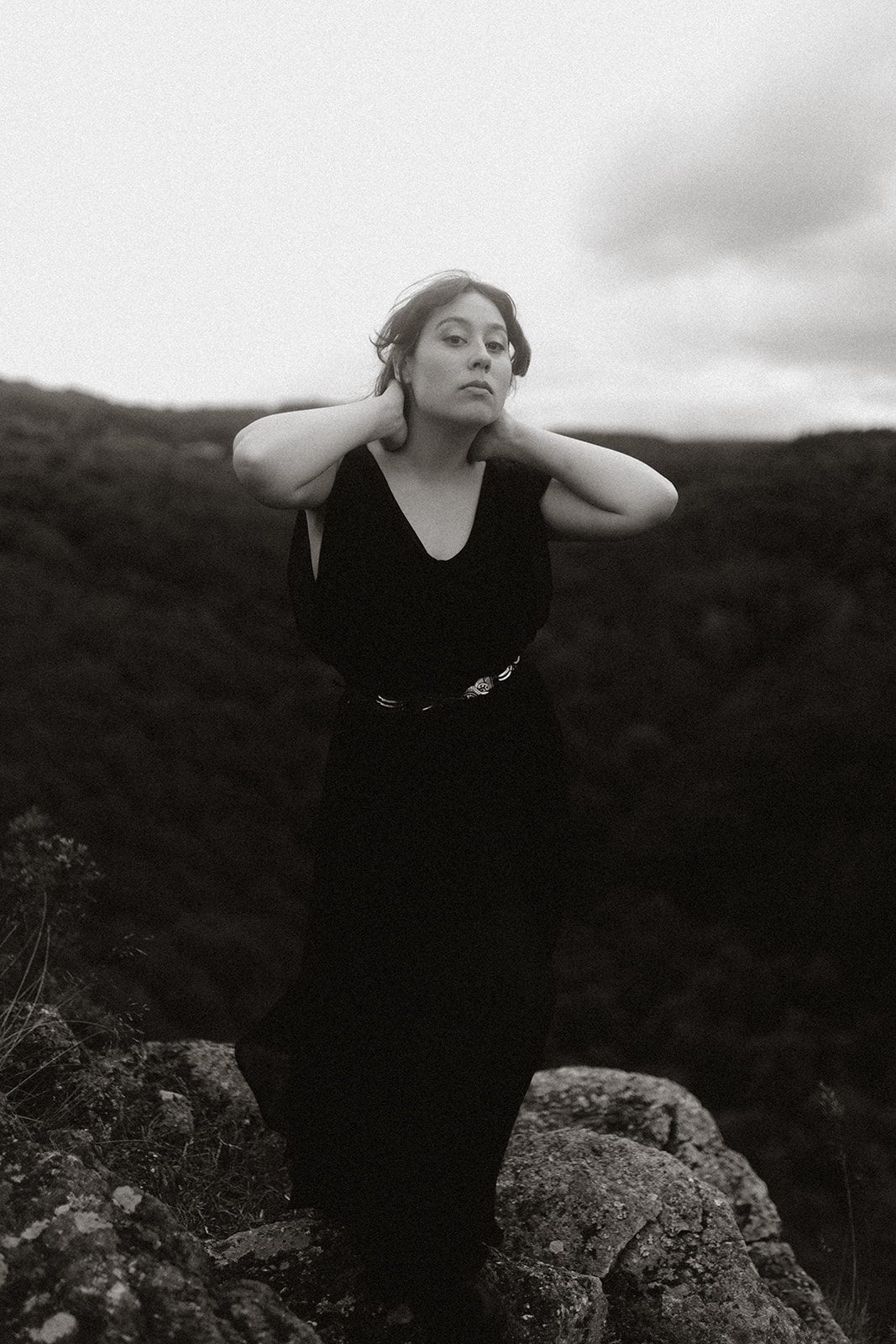 Anna Lê Quang debout dans un paysage de lande, en robe noire.